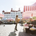 Full length side view of woman buying flowers at market stall in Malmo, Sweden
